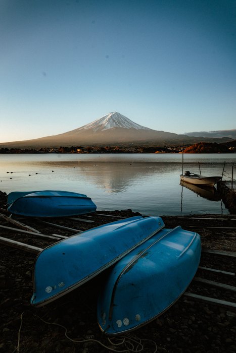 Canoe tirate a riva davanti al Monte Fuji riflesso nel lago