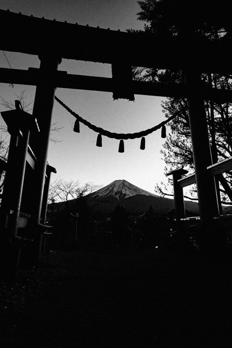Un torii in silhouette incornicia il Monte Fuji al crepuscolo