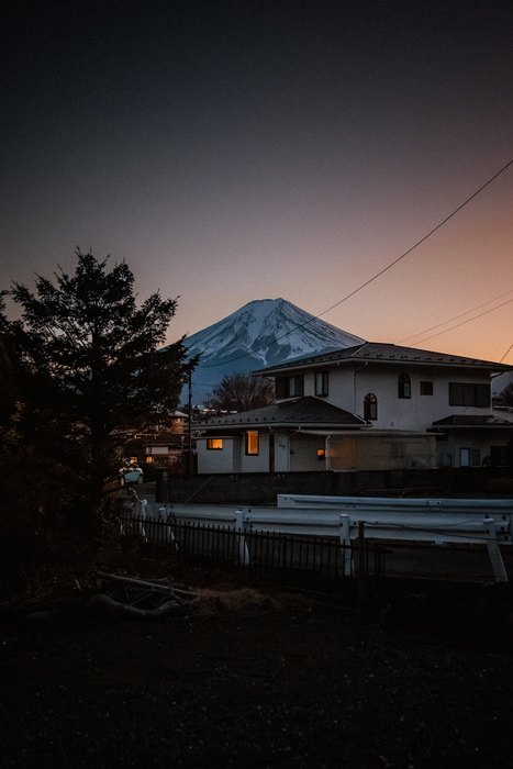 Il Monte Fuji appare oltre i tetti di Fujiyoshida durante l’ora blu