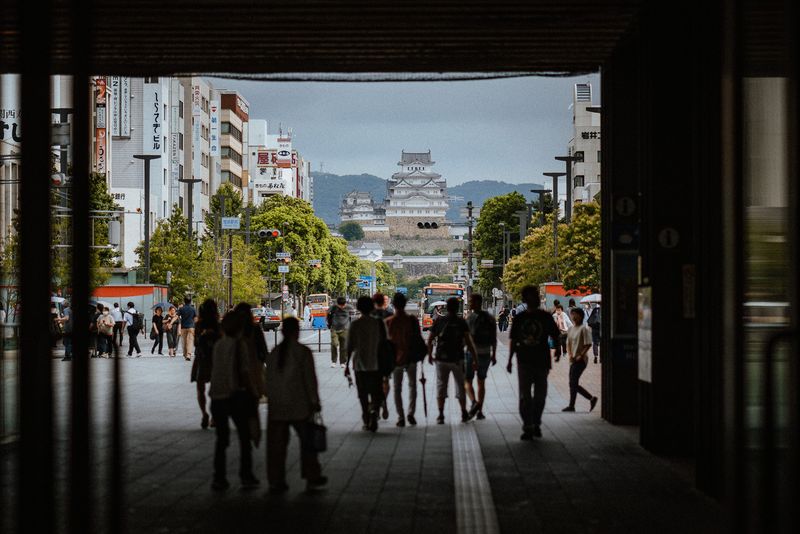 Il castello di Himeji incorniciato dall'uscita della stazione con i passanti in controluce, Himeji