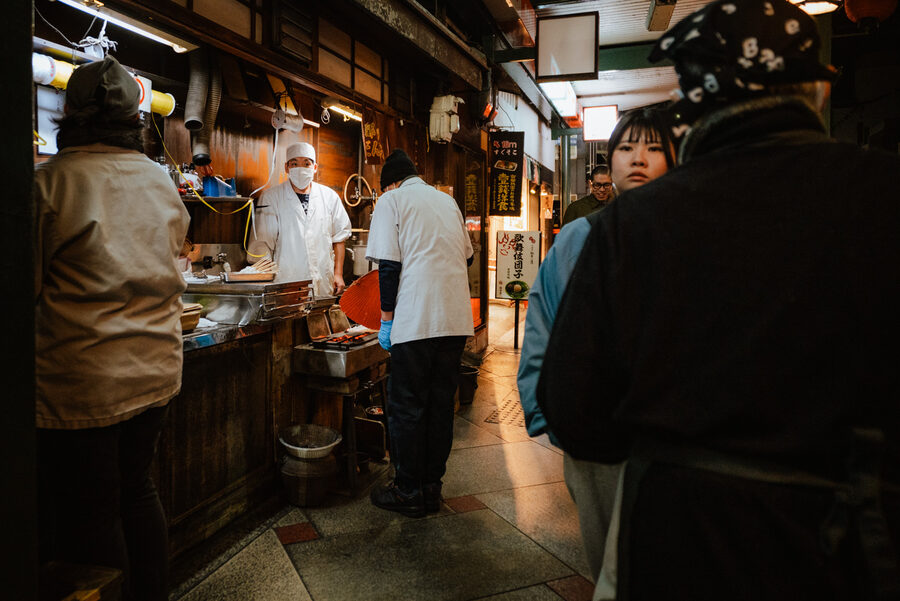 Clienti e cuochi attorno al banco di un locale, Kyoto
