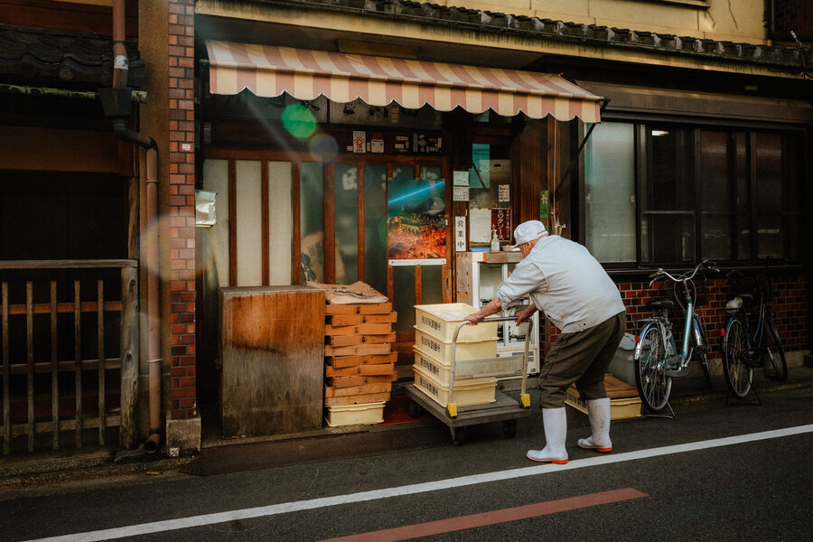Lavoratore sistema casse davanti a una bottega, Kyoto