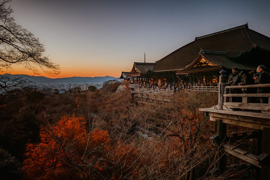 Il Kiyomizu-dera al tramonto con i visitatori sulla terrazza e il sole basso, Kyoto