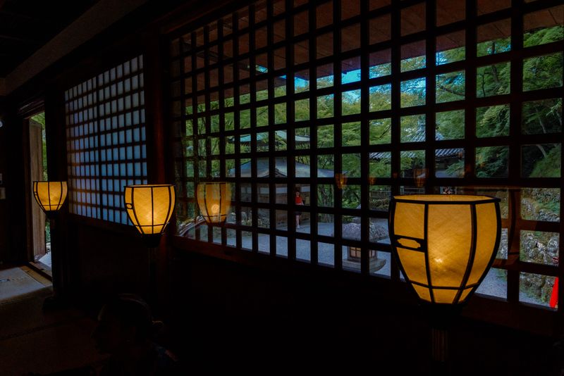 Fila di lanterne accese contro le finestre a graticcio di una sala del tempio, Kyoto