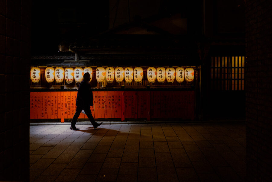 Passante davanti a una fila di lanterne accese, Kyoto