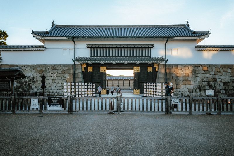 Il portale principale del castello Nijō al crepuscolo con una guardia e le lanterne, Kyoto