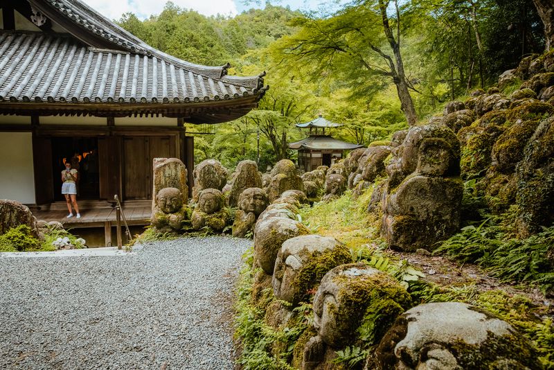 Visitatrice fotografa dalla veranda del tempio tra le statue rakan e la pagoda, Otagi Nenbutsu-ji, Kyoto