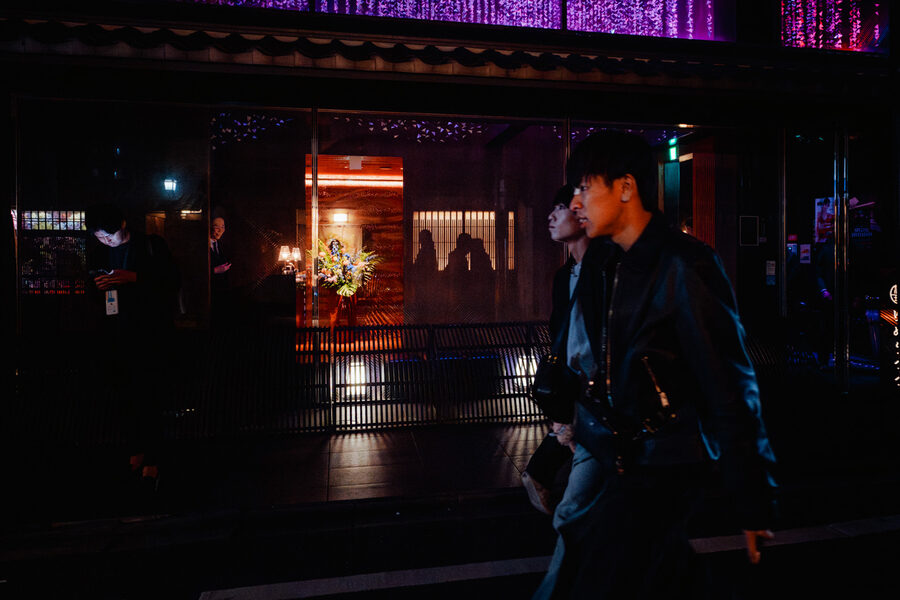 Passante attraversa una strada bagnata nella notte, Kyoto