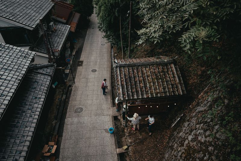 Veduta dall'alto di un vicolo di paese tra i tetti di tegole, alcune persone al lavoro, dintorni di Kyoto