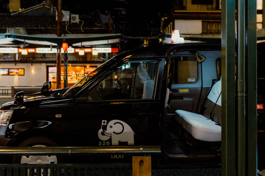 Taxi nero incorniciato dai riflessi della città, Kyoto
