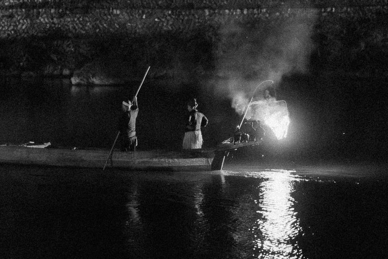 Pesca notturna con i cormorani (ukai) illuminata dal fuoco sul fiume, in bianco e nero, Arashiyama, Kyoto