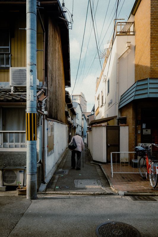 Anziano con il bastone si allontana in un vicolo stretto tra le case, Kyoto