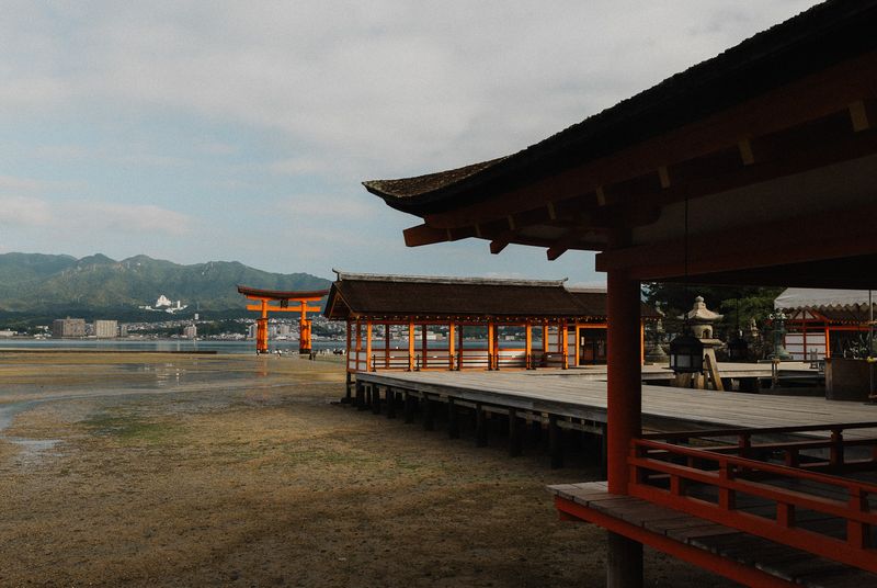 Veduta laterale del santuario di Itsukushima con il torii lontano oltre la sabbia scoperta, Miyajima