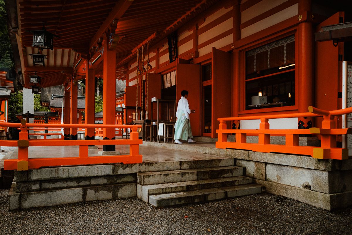 Un sacerdote shintoista attraversa il portico vermiglio del santuario, Kumano