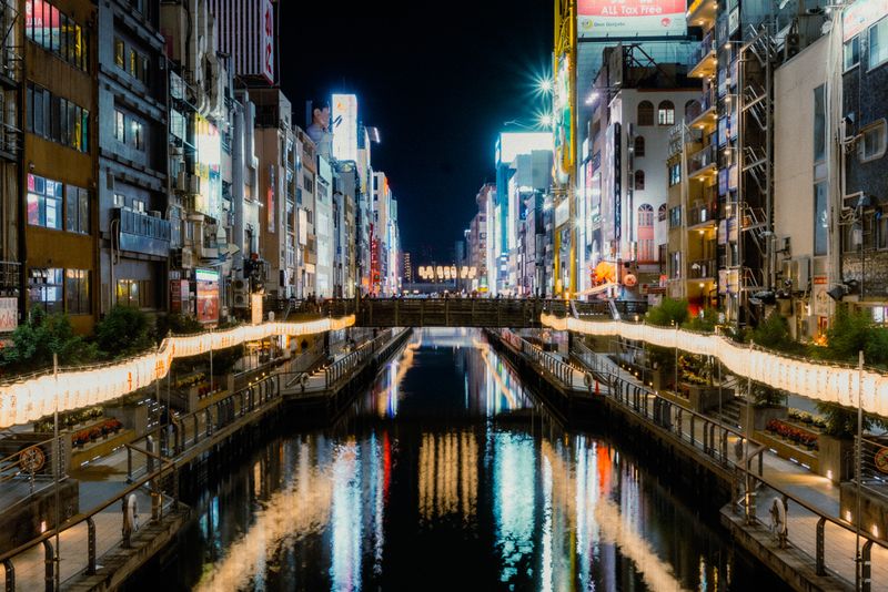 Il canale di Dōtonbori di notte con le insegne riflesse nell'acqua e le lanterne lungo le sponde, Osaka