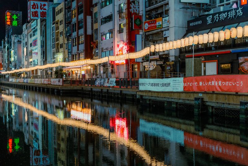 La sponda di Dōtonbori con la curva di lanterne accese e le insegne riflesse nel canale, Osaka