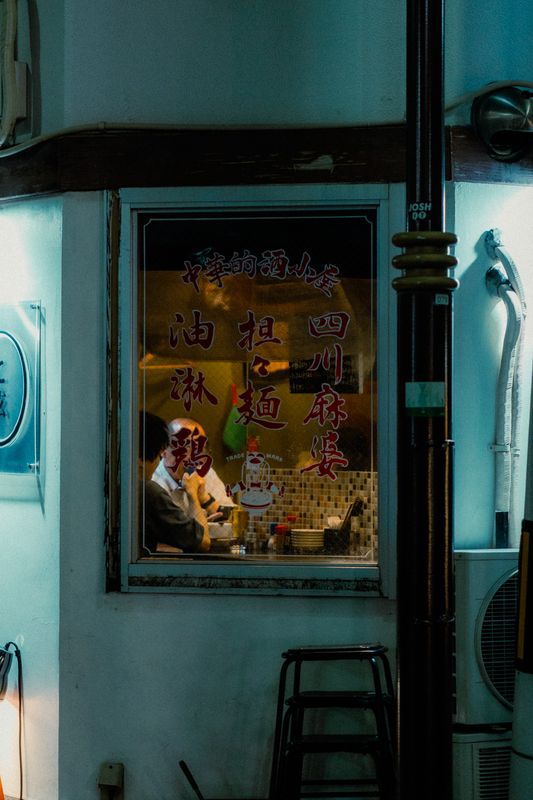 Cliente visto dalla finestra di una piccola trattoria cinese con i caratteri rossi sul vetro, di notte, Osaka