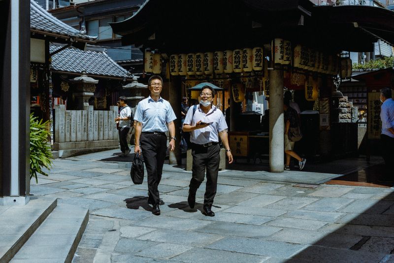 Due impiegati camminano sorridendo davanti al tempio con le lanterne di Hōzen-ji, Osaka