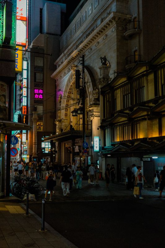 Il grande arco dell'edificio storico di Namba tra le insegne al neon e i passanti, di notte, Osaka
