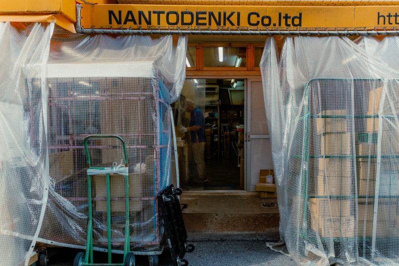 Ingresso di una bottega con teli di plastica e un lavoratore all'interno, Osaka