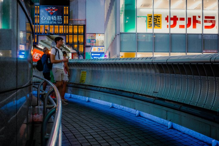 Osaka persona seduta marciapiede, fotografia di viaggio e street photography in Giappone