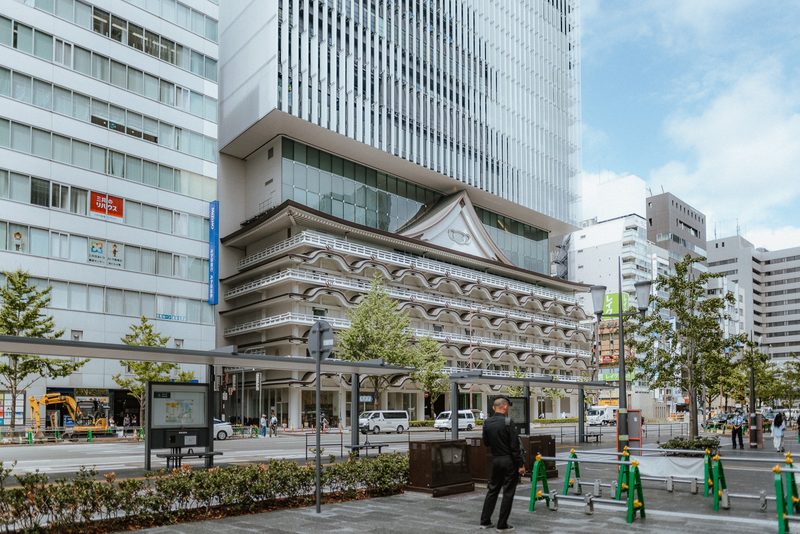 Il teatro kabuki Shōchikuza sotto un grattacielo, un uomo in attesa, Namba, Osaka