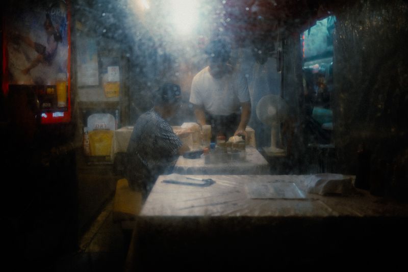 Cucina di un locale vista attraverso un vetro appannato e sporco, sagome sfocate al lavoro, Osaka