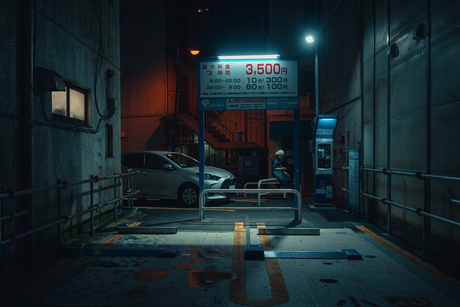 Parcheggio a pagamento di notte con il tabellone delle tariffe illuminato e una figura al distributore, Akihabara, Tokyo