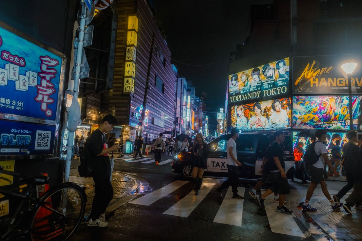 Passanti sulle strisce pedonali sotto i cartelloni degli host club, Kabukichō, Tokyo
