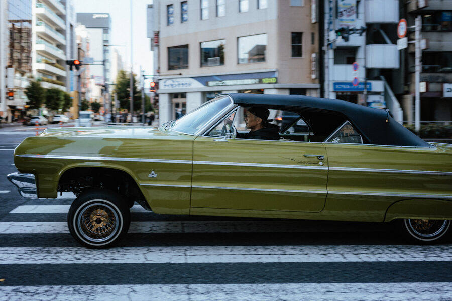 Auto americana verde attraversa una strada di Tokyo