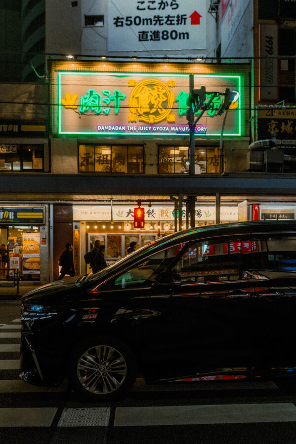 Auto sotto un’insegna verde nella notte, Tokyo