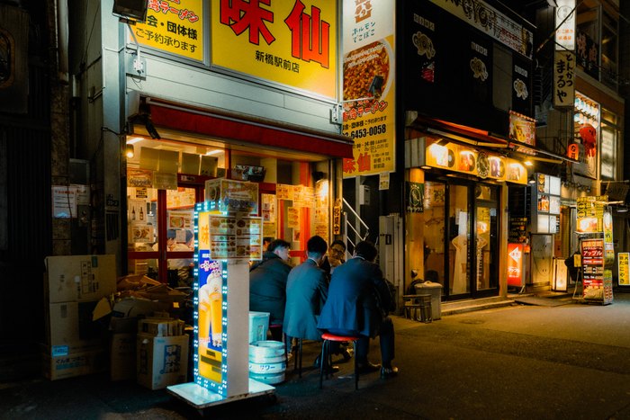 Clienti raccolti davanti a un banco illuminato nella notte di Tokyo