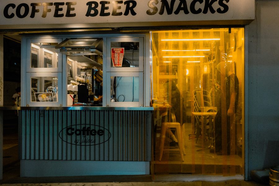 Piccolo locale con insegna Coffee Beer Snacks e tenda in plastica gialla che filtra la luce, Tokyo