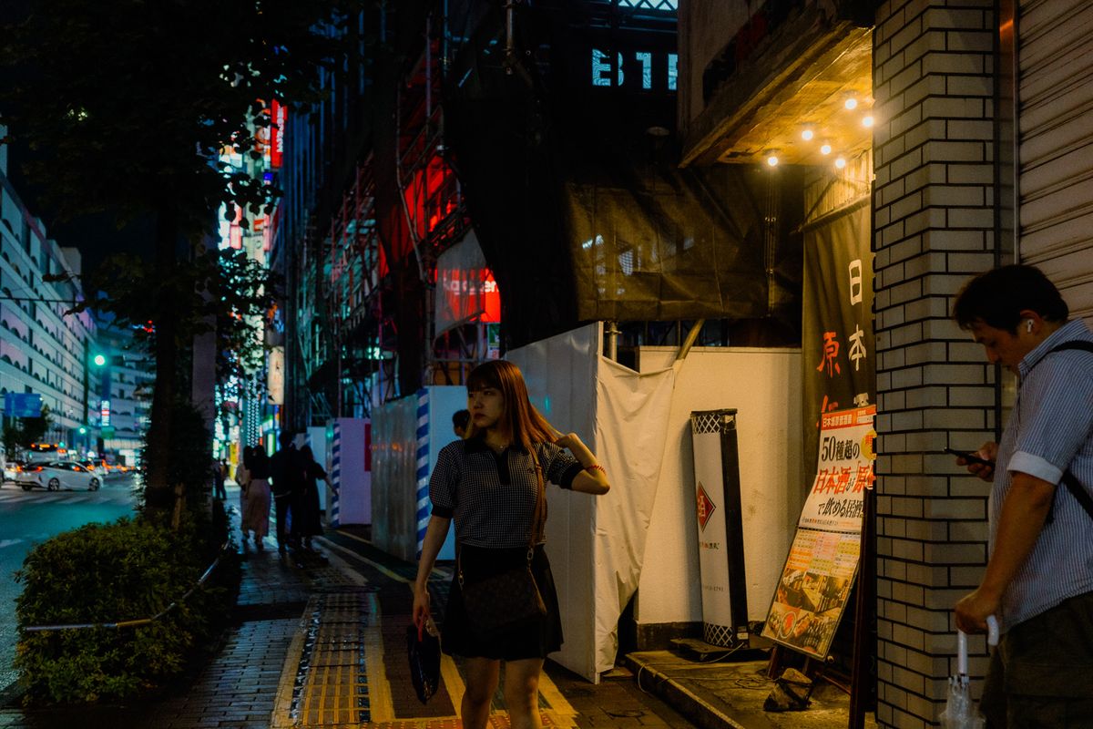 Donna cammina di notte lungo le impalcature di un cantiere, Shinjuku, Tokyo