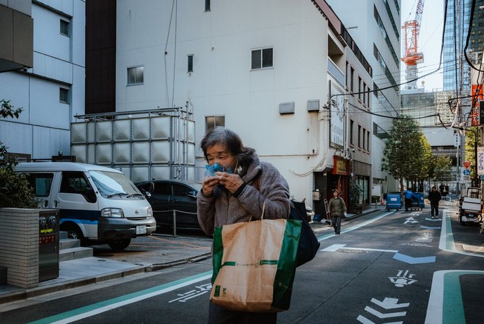 Una donna cammina con due borse della spesa in una strada di Tokyo