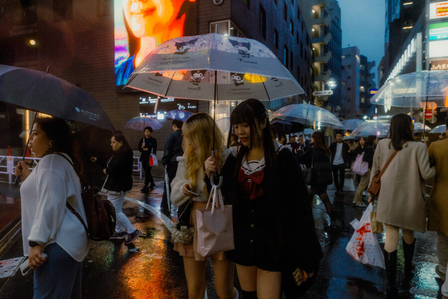 Folla con ombrelli attraversa una strada bagnata, Tokyo