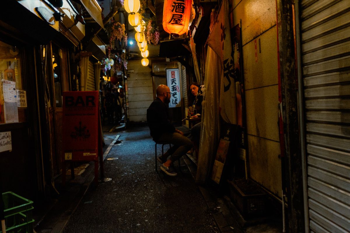 Coppia seduta a un tavolino nel vicolo delle lanterne del Golden Gai, Shinjuku, Tokyo