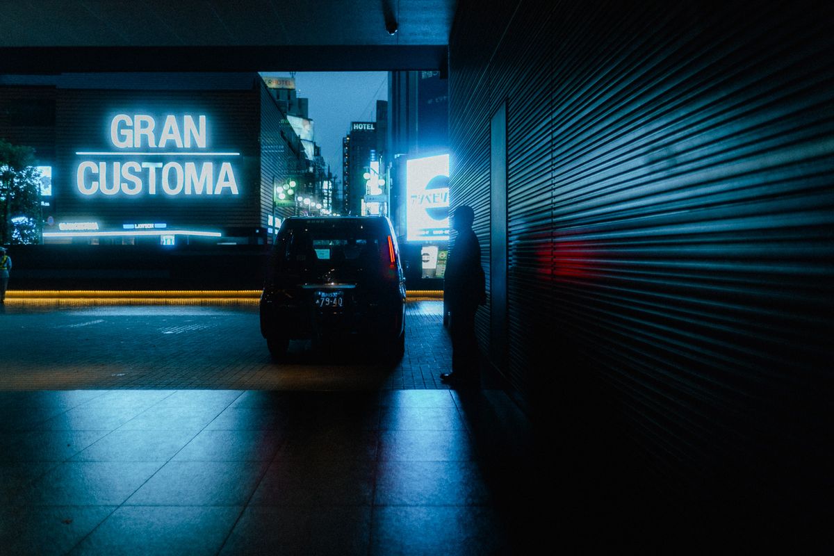 Uomo in silhouette accanto a un taxi davanti a una grande insegna luminosa, Shinjuku, Tokyo