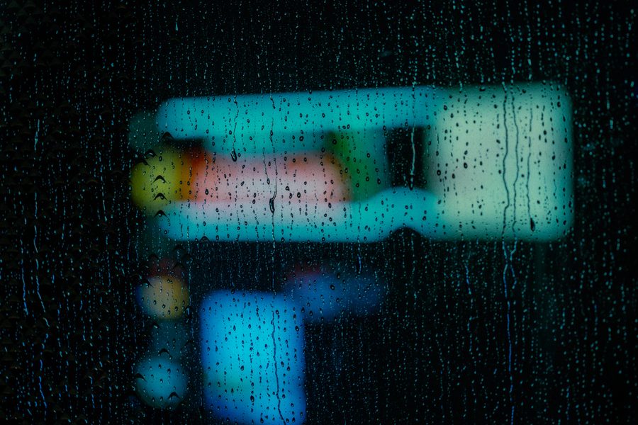 Insegna al neon sfocata dietro un vetro rigato dalla pioggia, astrazione notturna, Tokyo