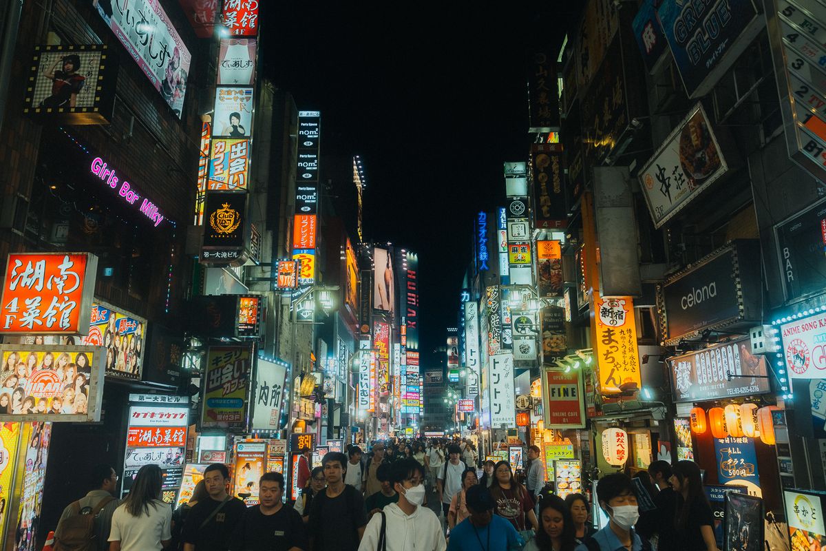 La folla nella via delle insegne verticali di Kabukichō, Tokyo
