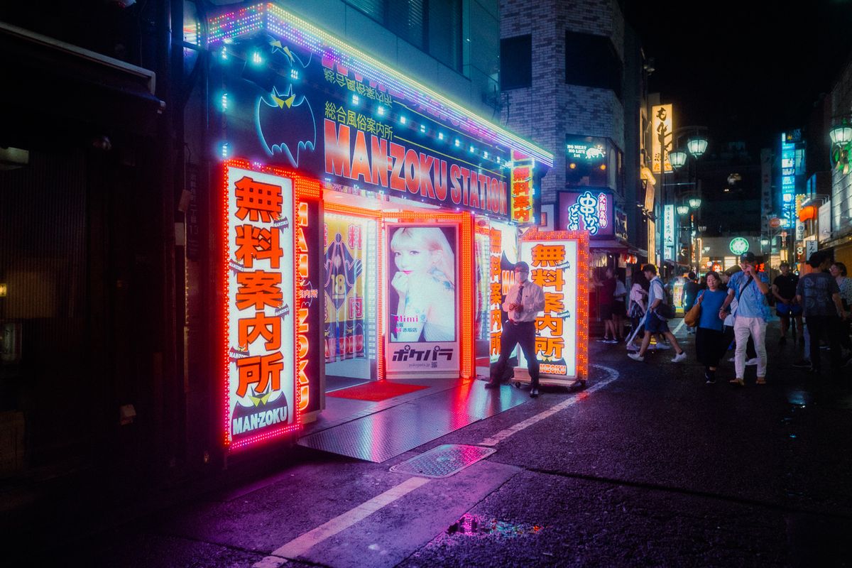 Insegne rosa e rosse di un locale notturno all’angolo della strada, Kabukichō, Tokyo