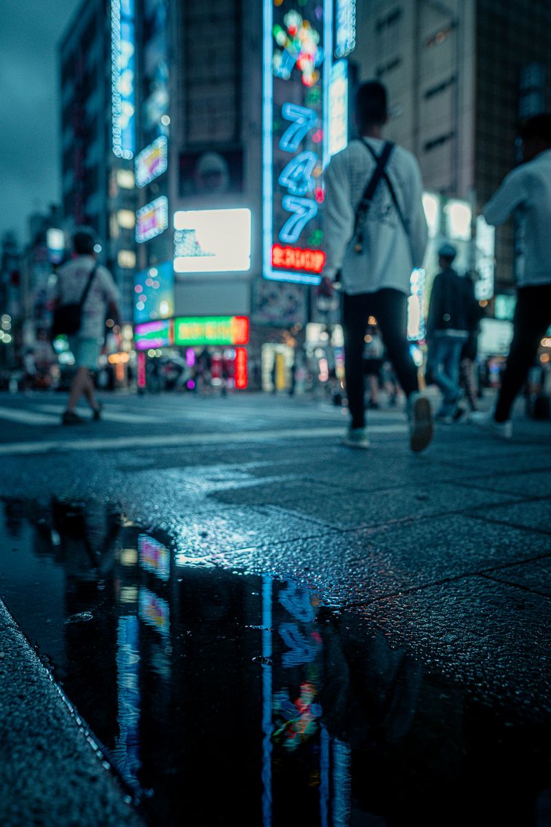 Neon riflessi in una pozzanghera dopo la pioggia, Kabukichō, Tokyo