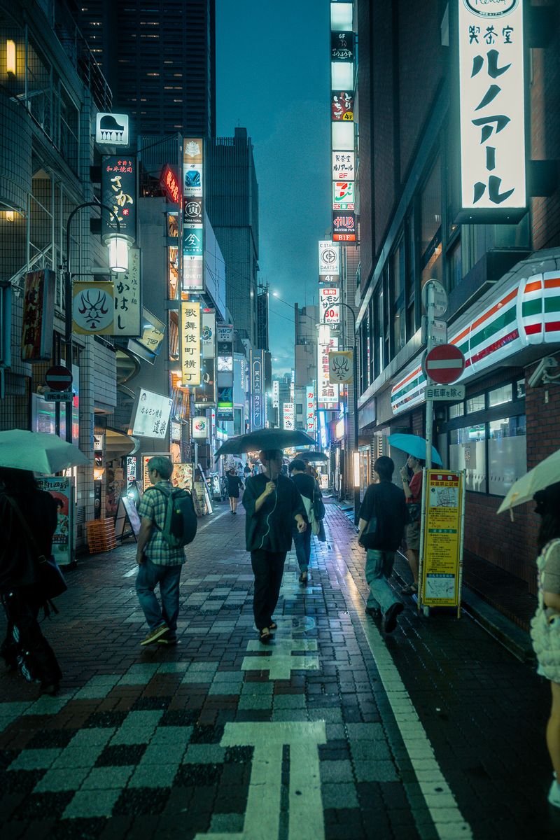 Passanti con l’ombrello nel vicolo di Kabukichō sotto la pioggia, Tokyo