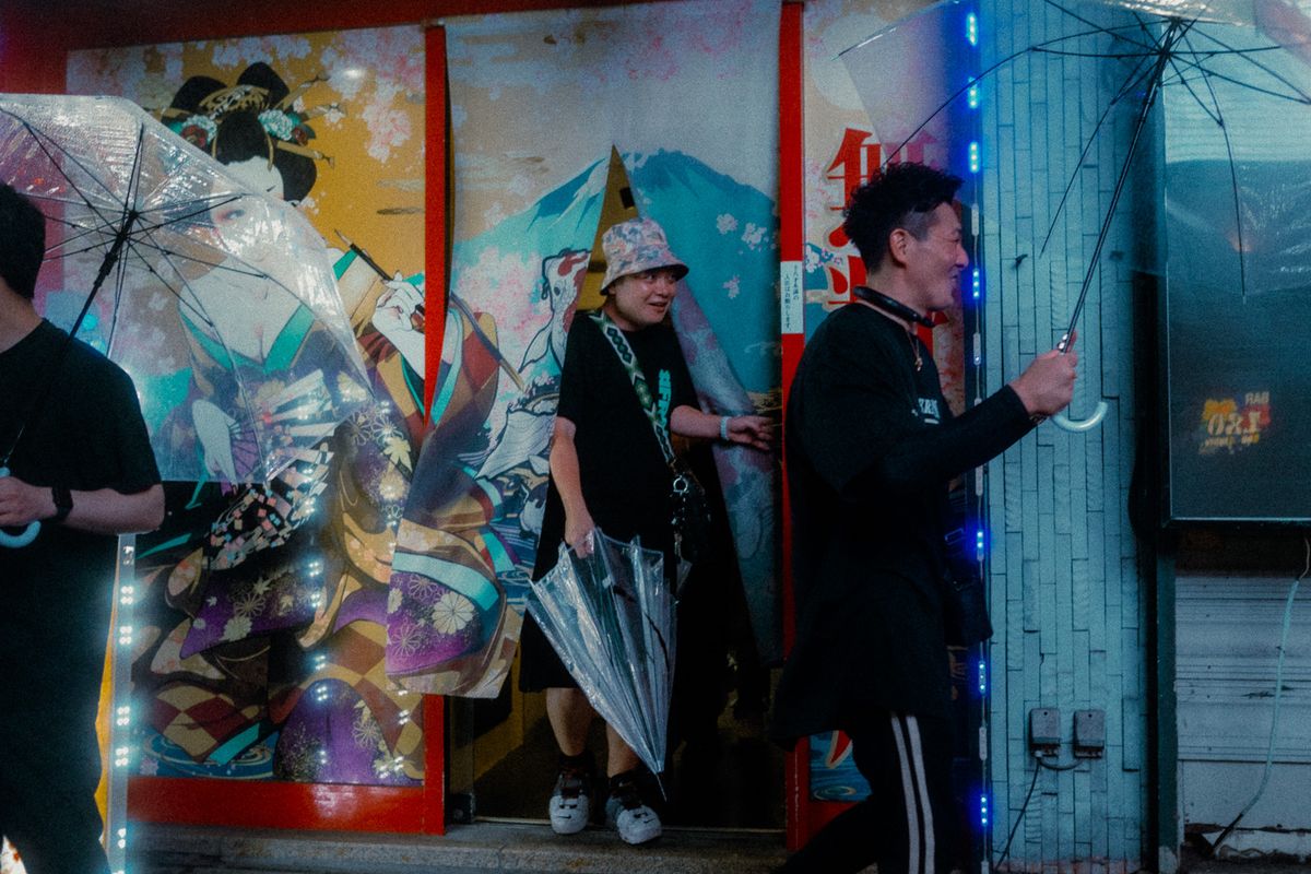 Passanti con ombrelli trasparenti davanti a un murale in stile ukiyo-e, Kabukichō, Tokyo