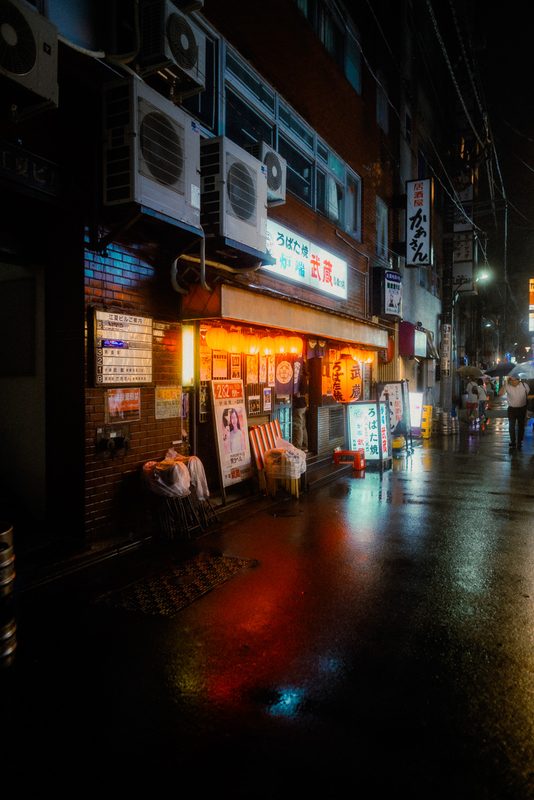 Izakaya Robata Musashi con lanterne rosse in un vicolo bagnato dalla pioggia, di notte, Tokyo