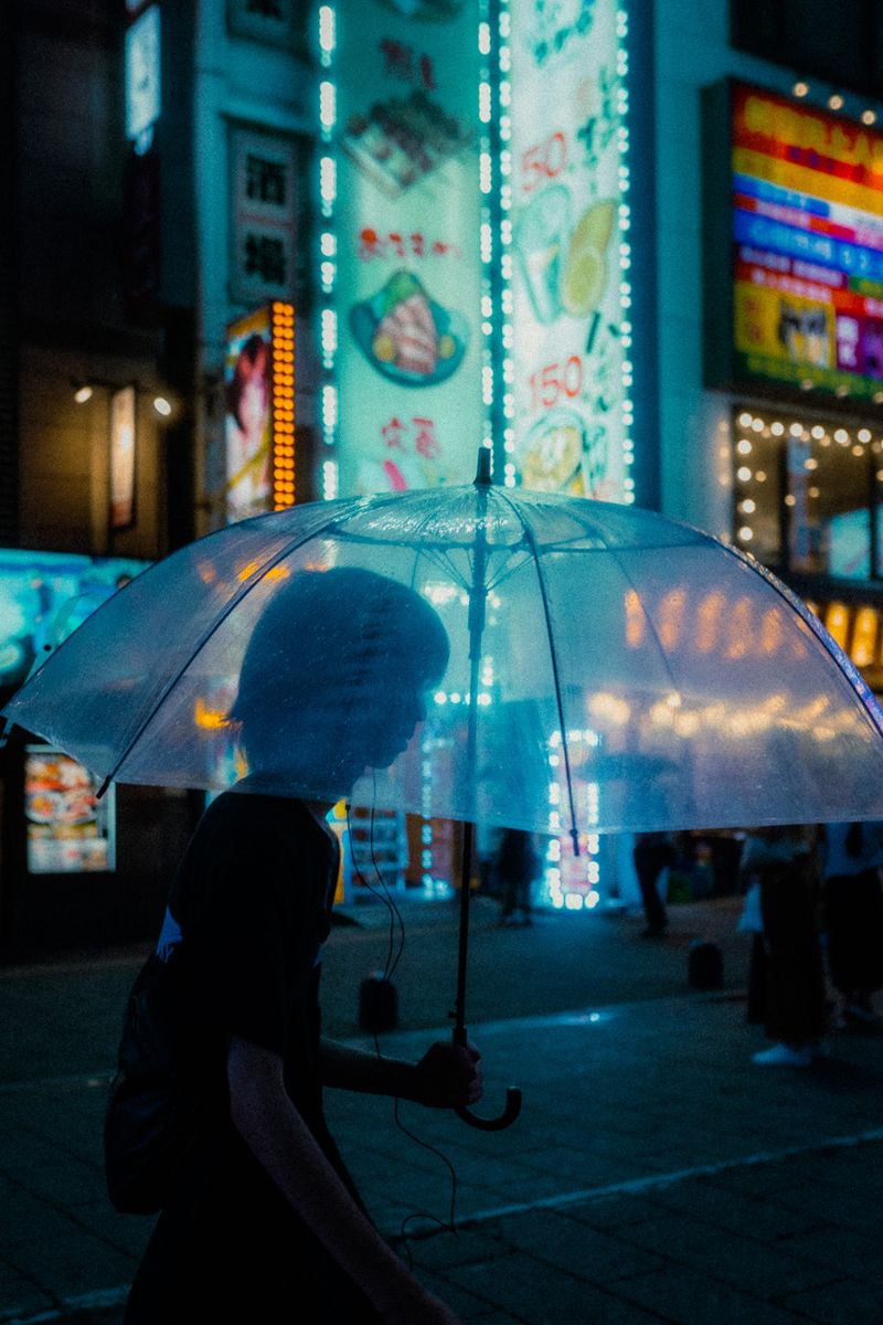 Silhouette dietro un ombrello trasparente illuminato dai neon, Shinjuku, Tokyo