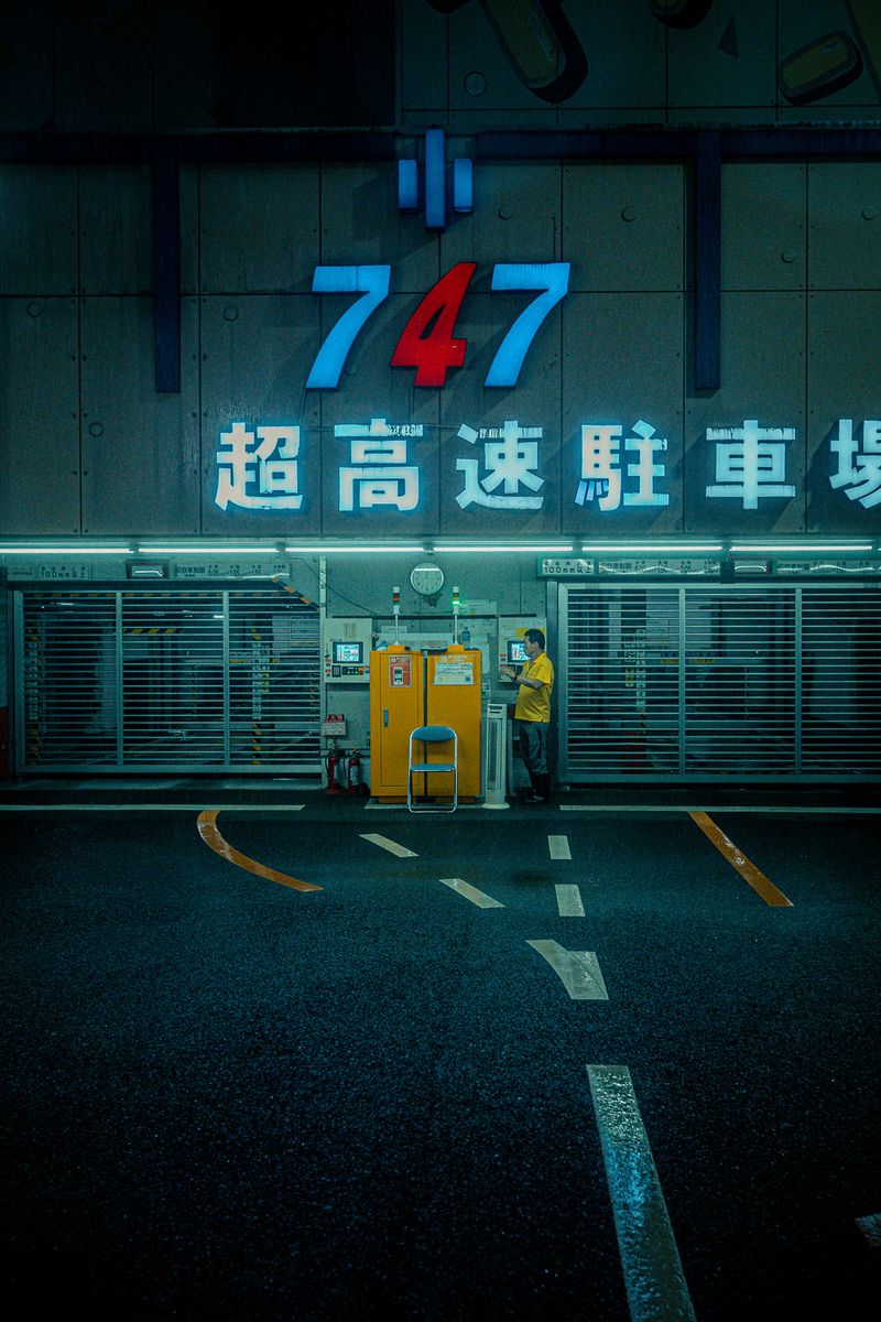 Addetto in camicia gialla al banco di un parcheggio automatico, Shinjuku, Tokyo