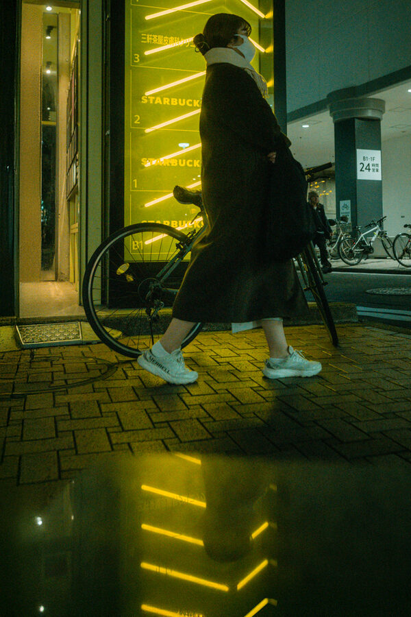 Passante attraversa una pozza di luce gialla, Tokyo
