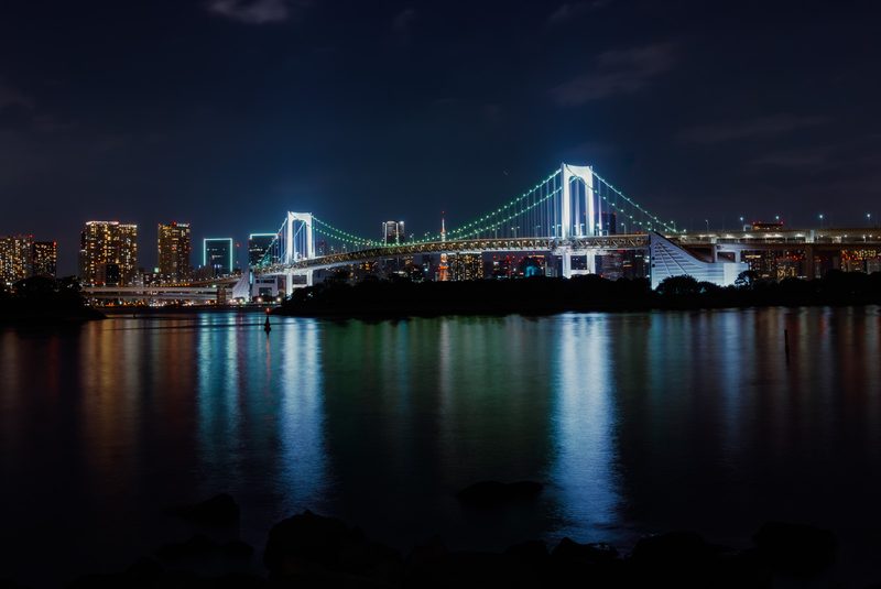 Il Rainbow Bridge illuminato di notte riflesso sull'acqua, baia di Tokyo