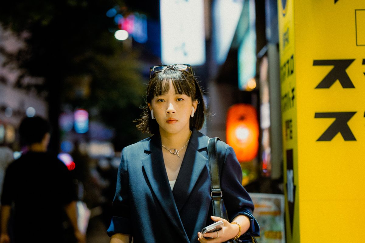 Ritratto di strada di una giovane donna accanto a un’insegna gialla, Tokyo